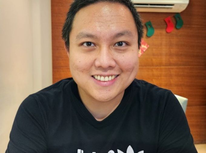 smiling person with short dark hair wearing black adidas tshirt