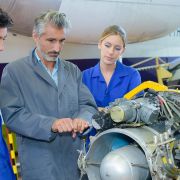 Three individuals working on airplane equipment