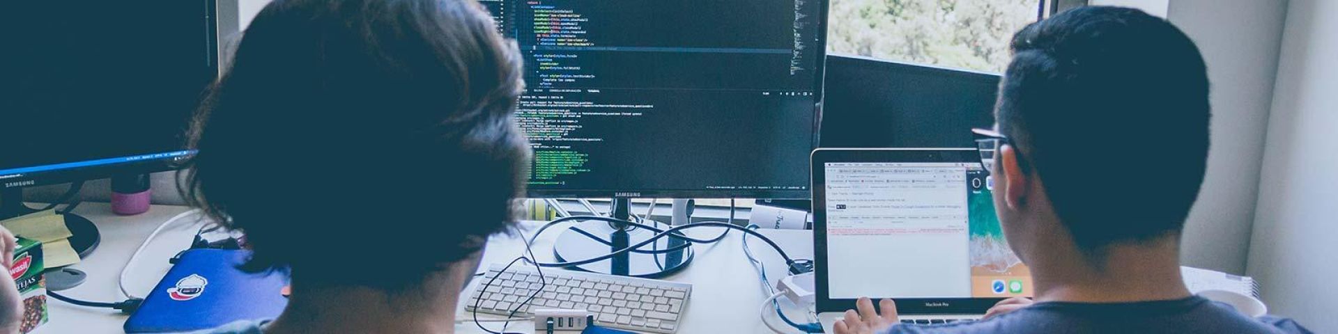 Two humans looking at code on computer screen