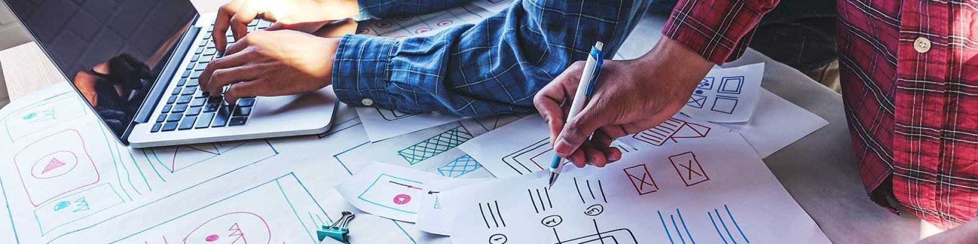Students drawing on paper and using a laptop
