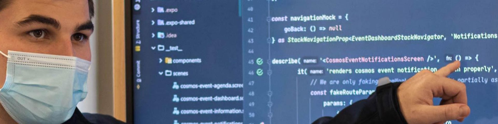 Student wearing surgical mask pointing at code on a screen