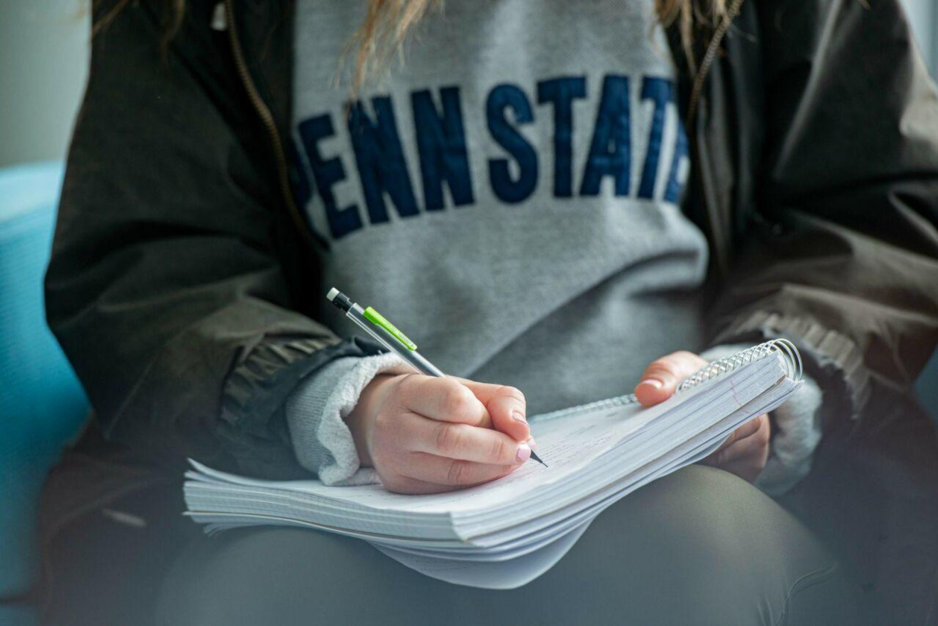 student in penn state sweatshirt writing in notebook