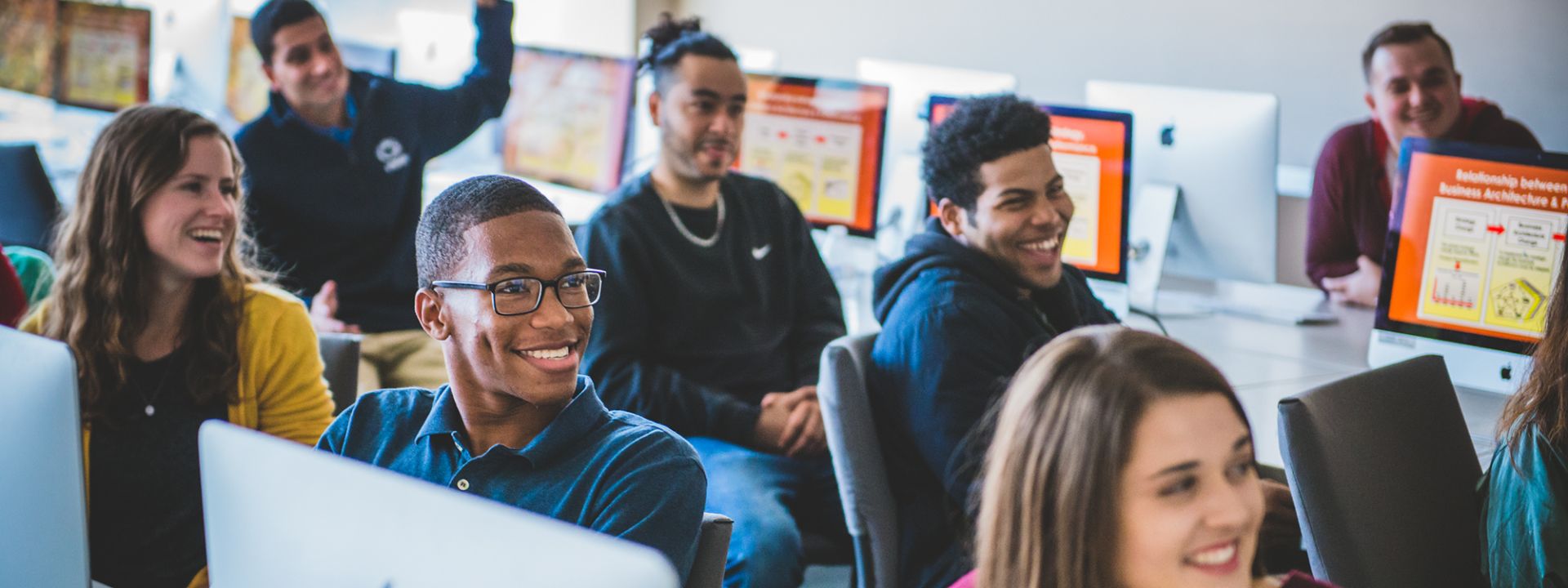 Students learn at computers in a classroom.