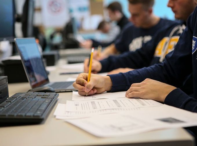 Students with laptops writing on paper