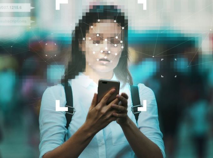 A woman using a smartphone with facial recognition technology.