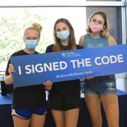 Students hold a sign "I Signed the Code" indicating they signed the IST Honor Code.