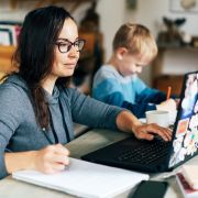 Adult student learning online, working on school work at home beside child.