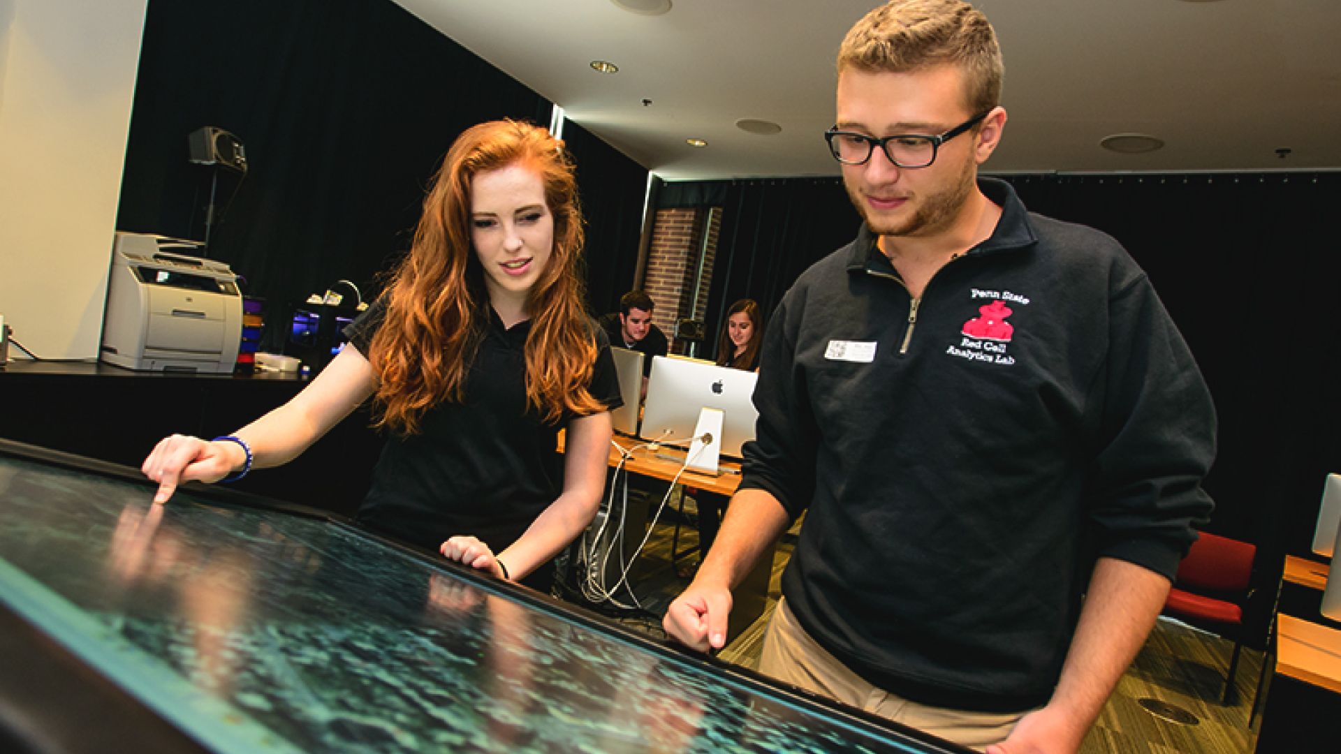 Students interact with a data visualization on a digital table.