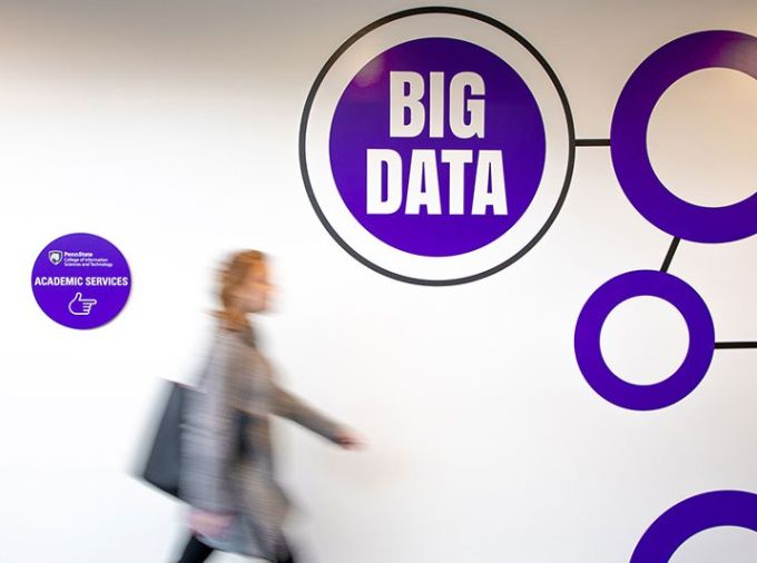 Woman walking by a white wall with the words BIG DATA written on it