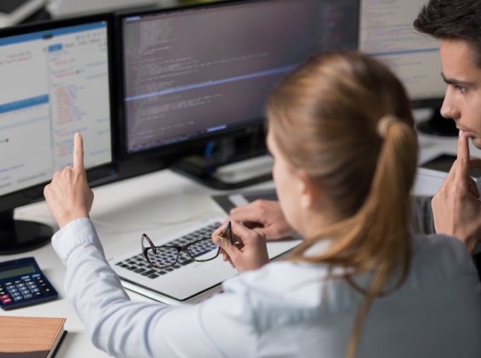 Students reviewing code on computer screen.