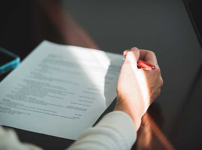 Person holding a red pen correcting a paper