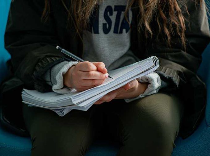 Woman writing on notebook paper with pencil