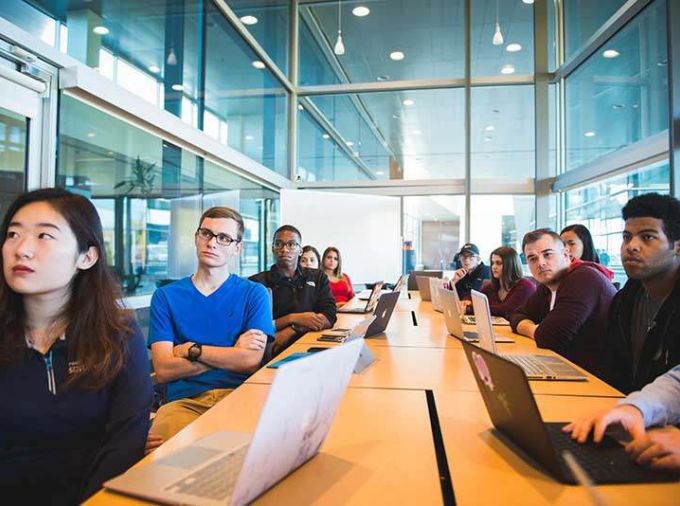 Students in glass room around table with laptops