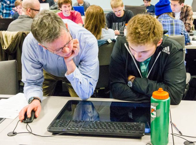 Teacher helping student on flat top computer in classroom