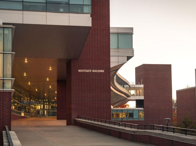 Brick and glass campus building with a curved walkway and atrium