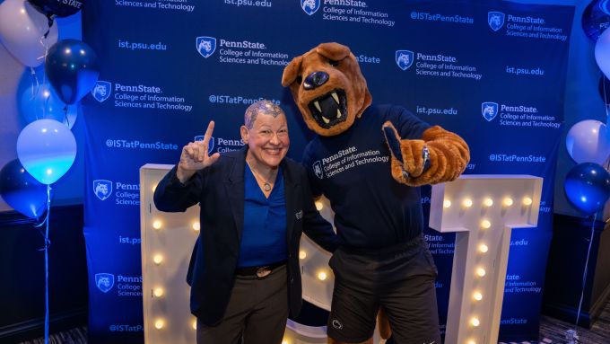 Andrea Tapia and the Nittany Lion standing in front of giant I-S-T letters, giving a number 1 sign