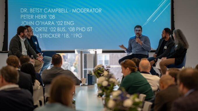 A panel of presenters speak to an audience.