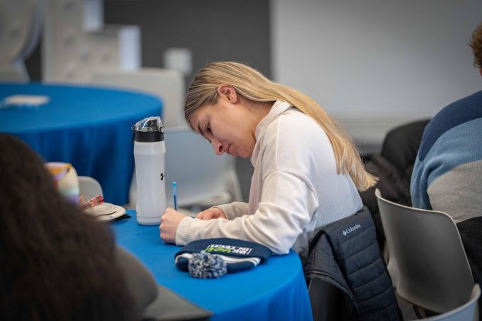 A student writes on a notecard at a table.