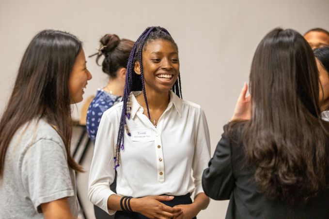 A student smiles while talking to other students.