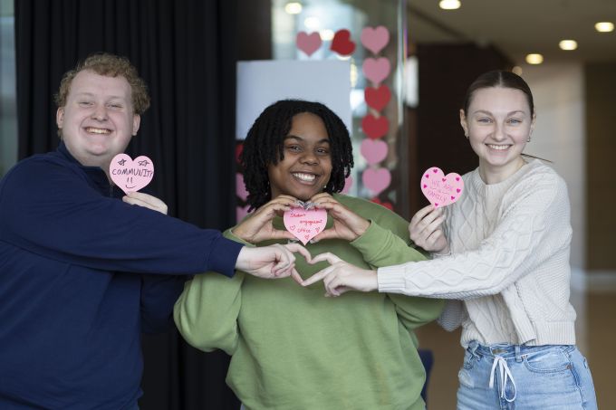 Smiling students holding up paper hearts.