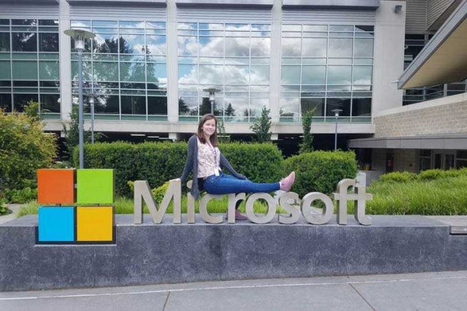 Student intern sitting on top of Microsoft sign.
