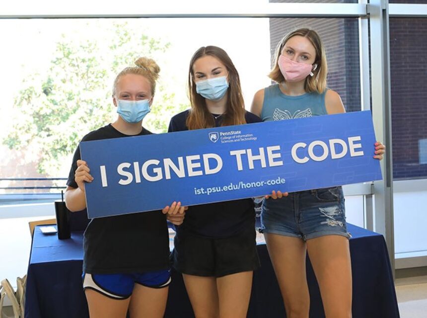 Students hold a sign "I Signed the Code" indicating they signed the IST Honor Code.