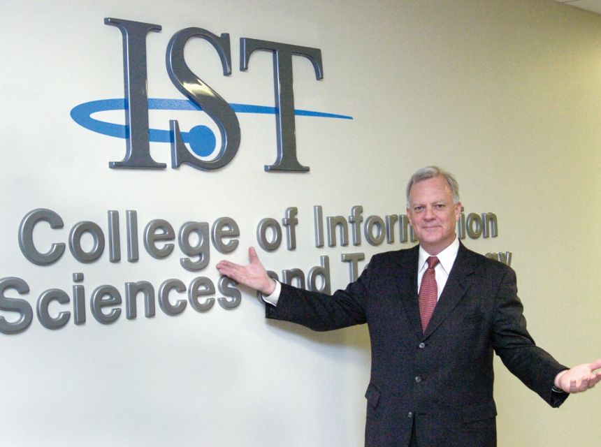 Jim Thomas stands in front of a new College of IST sign