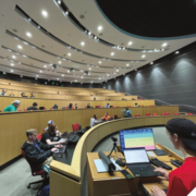 Students work at computers in a large classroom.