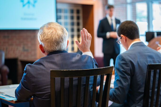 A person raises their hand to ask a question of a student presenter.