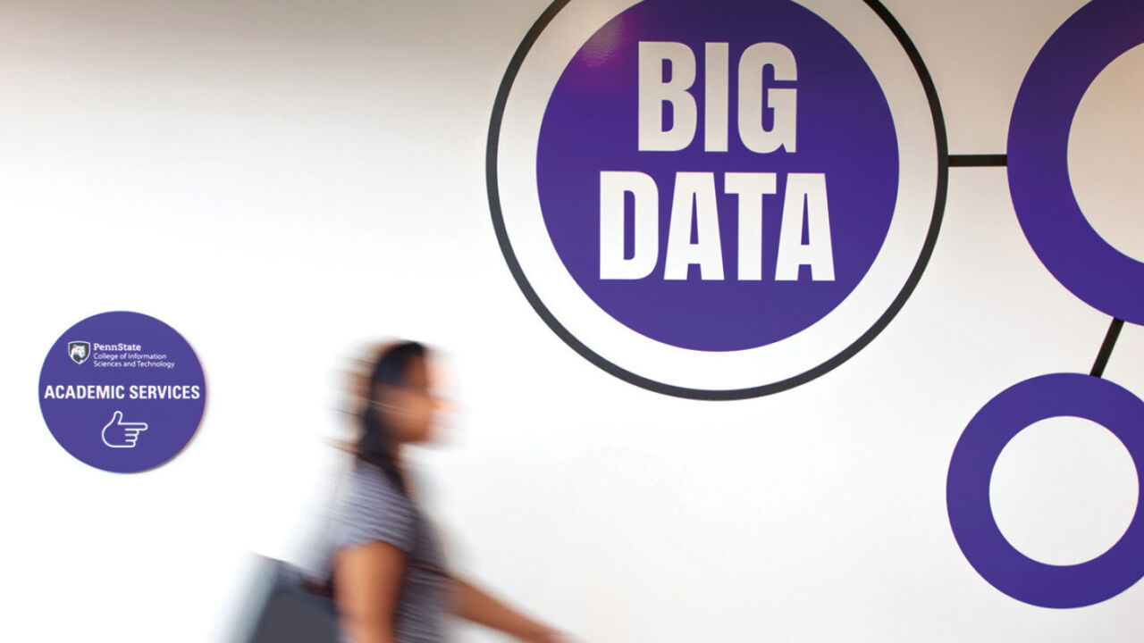 Blurry student shot in time-lapse in front of a sign that reads Big Data