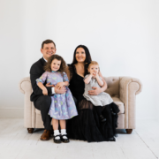 A couple poses on a love seat with their two children
