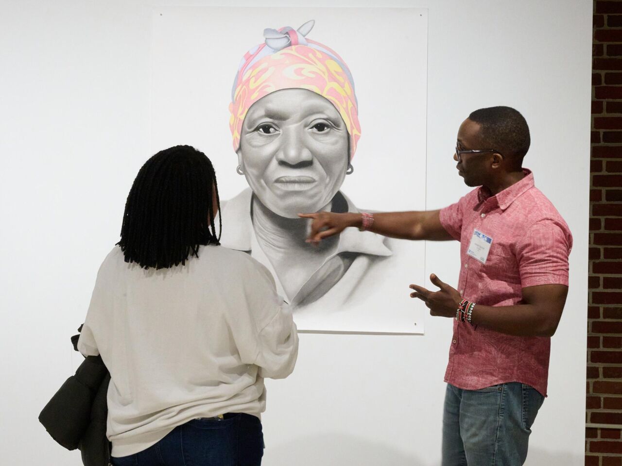 two people examine hanging artwork