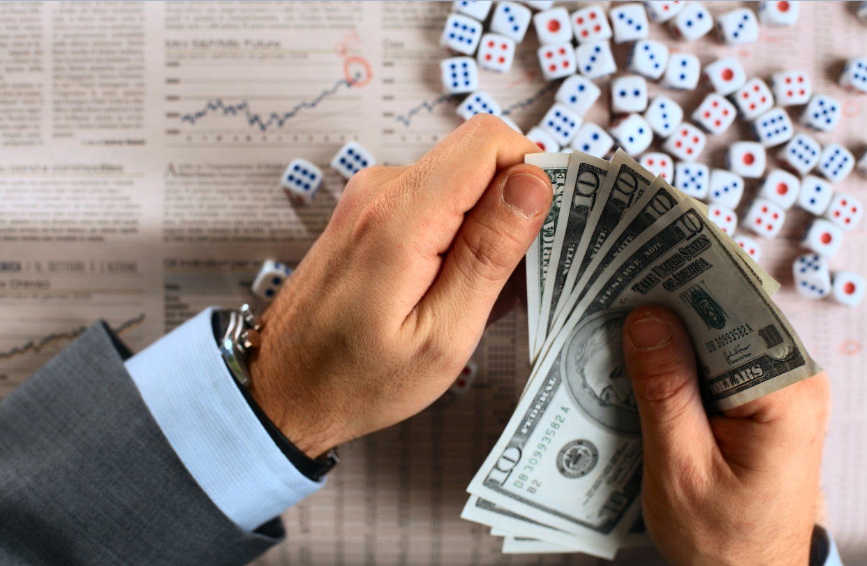 hands holding dollars at roulette table